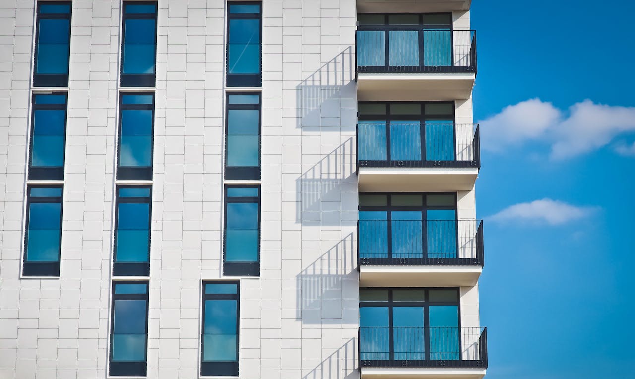 portfolio-06 Contemporary urban apartment building with framed glass windows against clear blue sky.