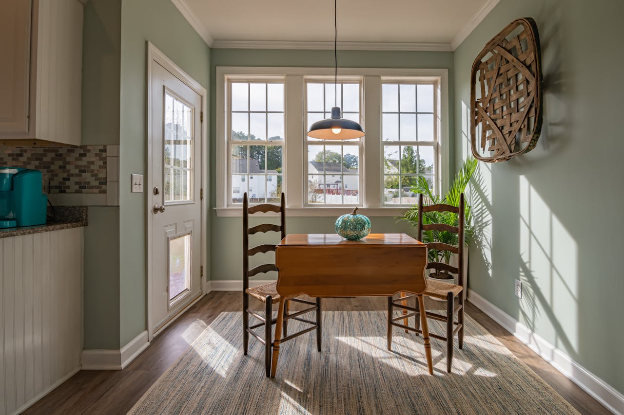 portfolio-03 Bright dining area with wooden furniture and large windows showcasing natural light.